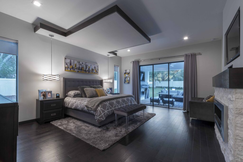 The Design Tourist's personal home features a master bedroom that incorporates her design formula: Notice the doses of metallic with the hanging pendants on either side of the bed and the stainless steel fireplace. Texture comes from the grey shag rug, faux fur accent pillows and blanket that complement the natural wood floors.