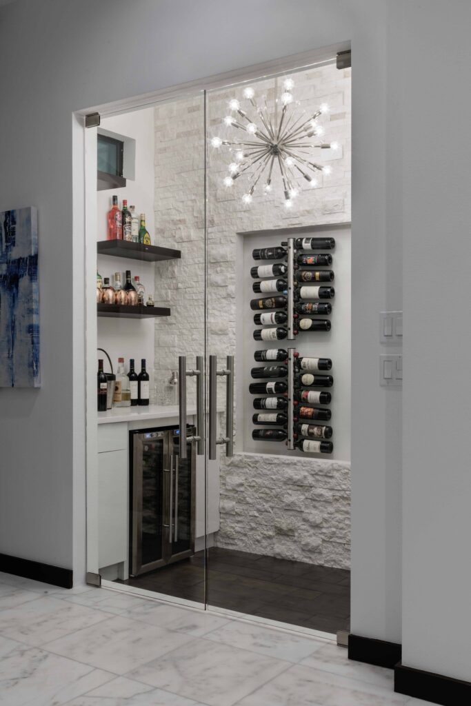 The wine room in The Design Tourist's personal residence draws the eye to an on-trend "Sputnik" light fixture. The wood floors and white ledgestone wall echo the home's central design details. 