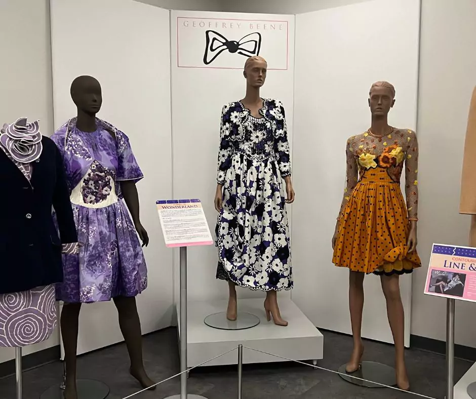 A Geoffrey Beene exhibit featuring mannequins dressed in floral and geometric print dresses, including a standout yellow polka-dot design with mesh sleeves. Informational signage provides historical insights into his fashion innovations.
