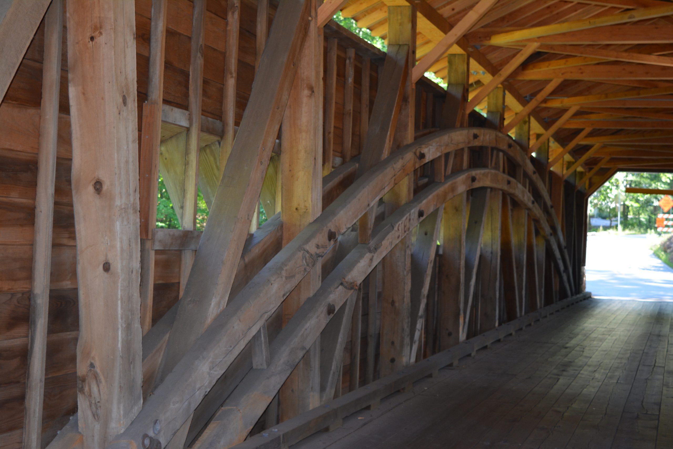 Close-up of the wooden Burr arch-truss framework inside a covered bridge, highlighting the historic carpentry and beam structure.