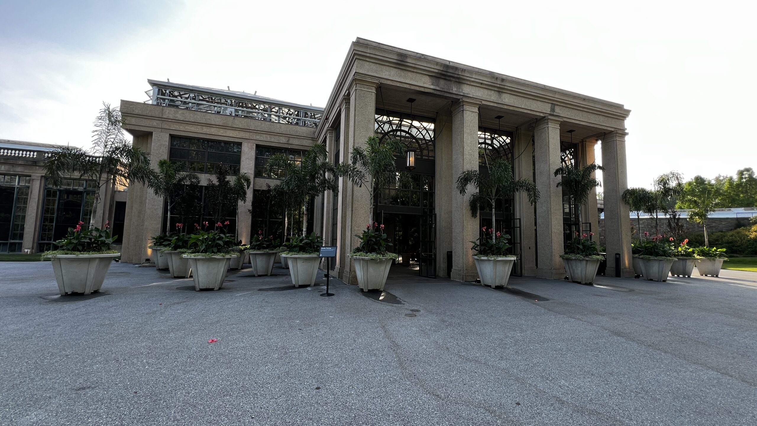 Main entrance of Longwood Gardens with large columns, tall glass windows, and decorative potted palms