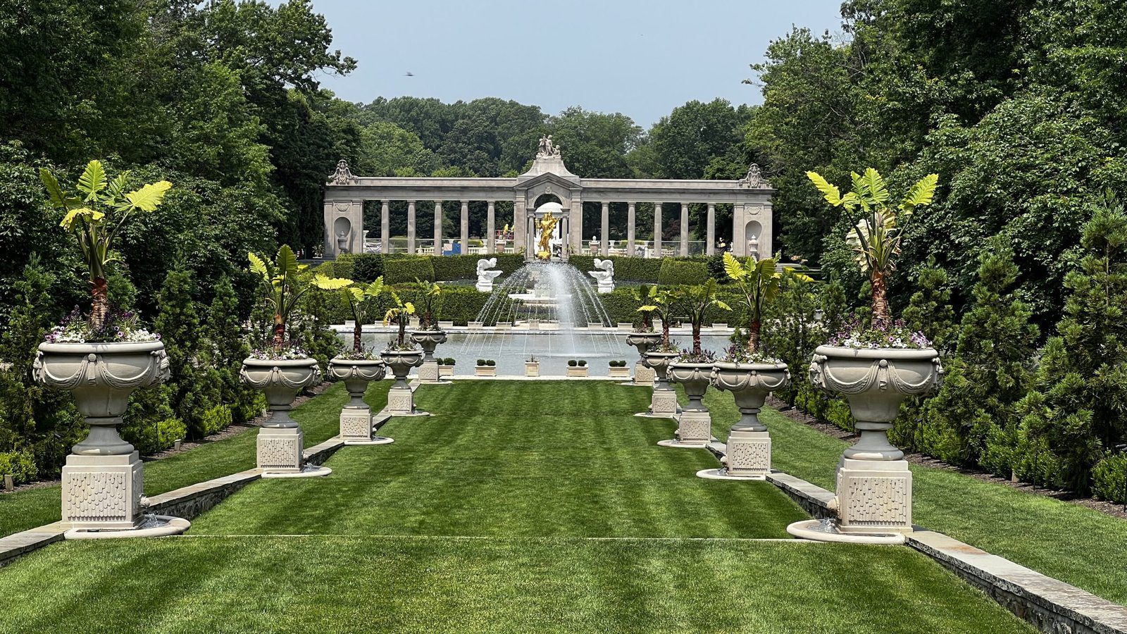 Symmetrical lawn and ornate urns leading to a grand fountain display at Longwood Gardens