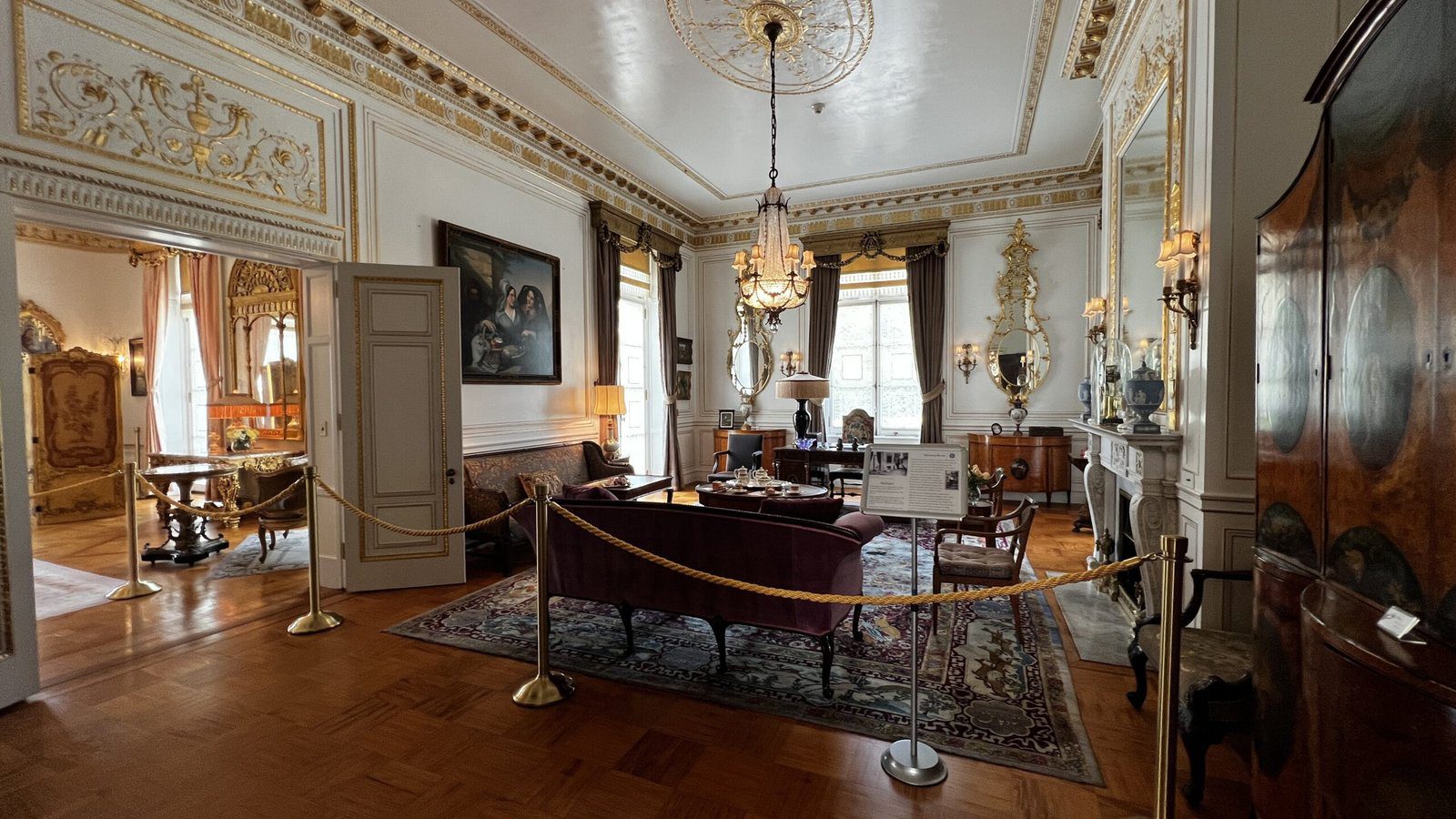 Elegant sitting room at Nemours Estate with chandeliers, antique furniture, and gilded mirror frames