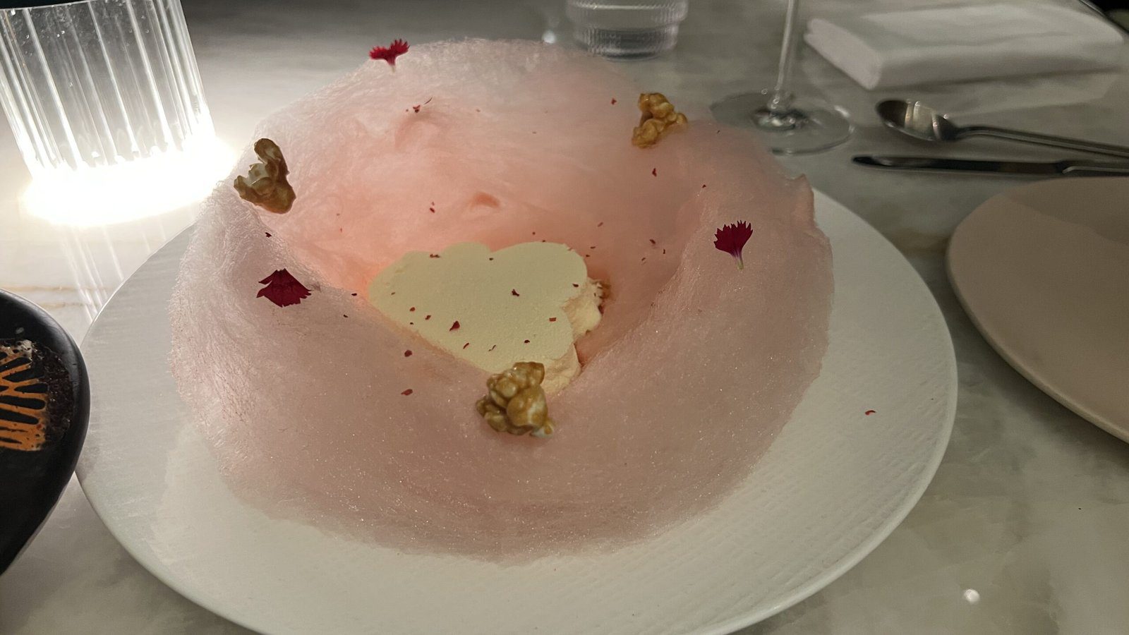 Whimsical pink cotton candy nest dessert with a heart-shaped mousse center and candied walnuts at Le Jardinier.