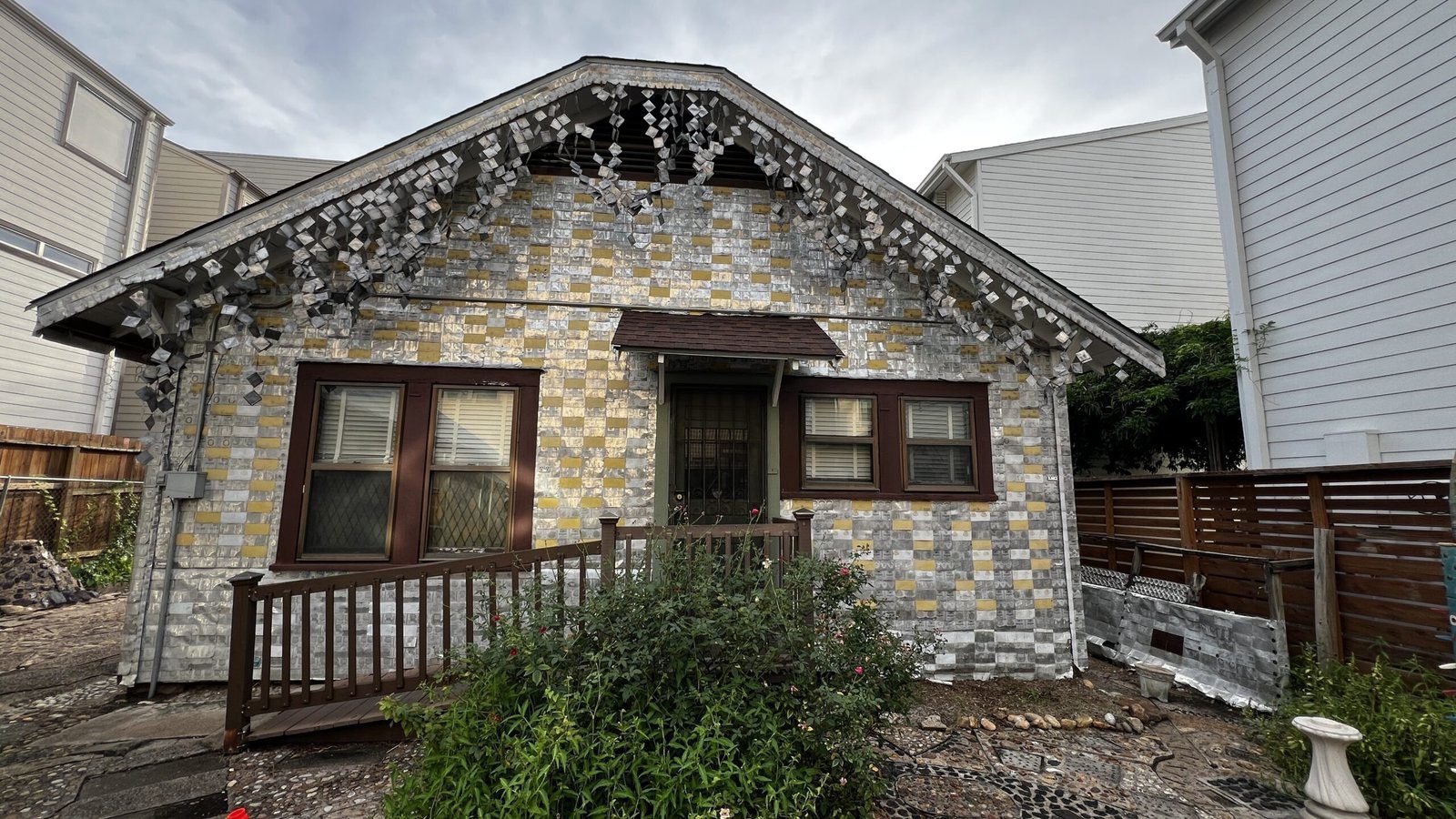 Front façade of the Beer Can House, covered in patterned aluminum can siding with decorative elements on the roof.