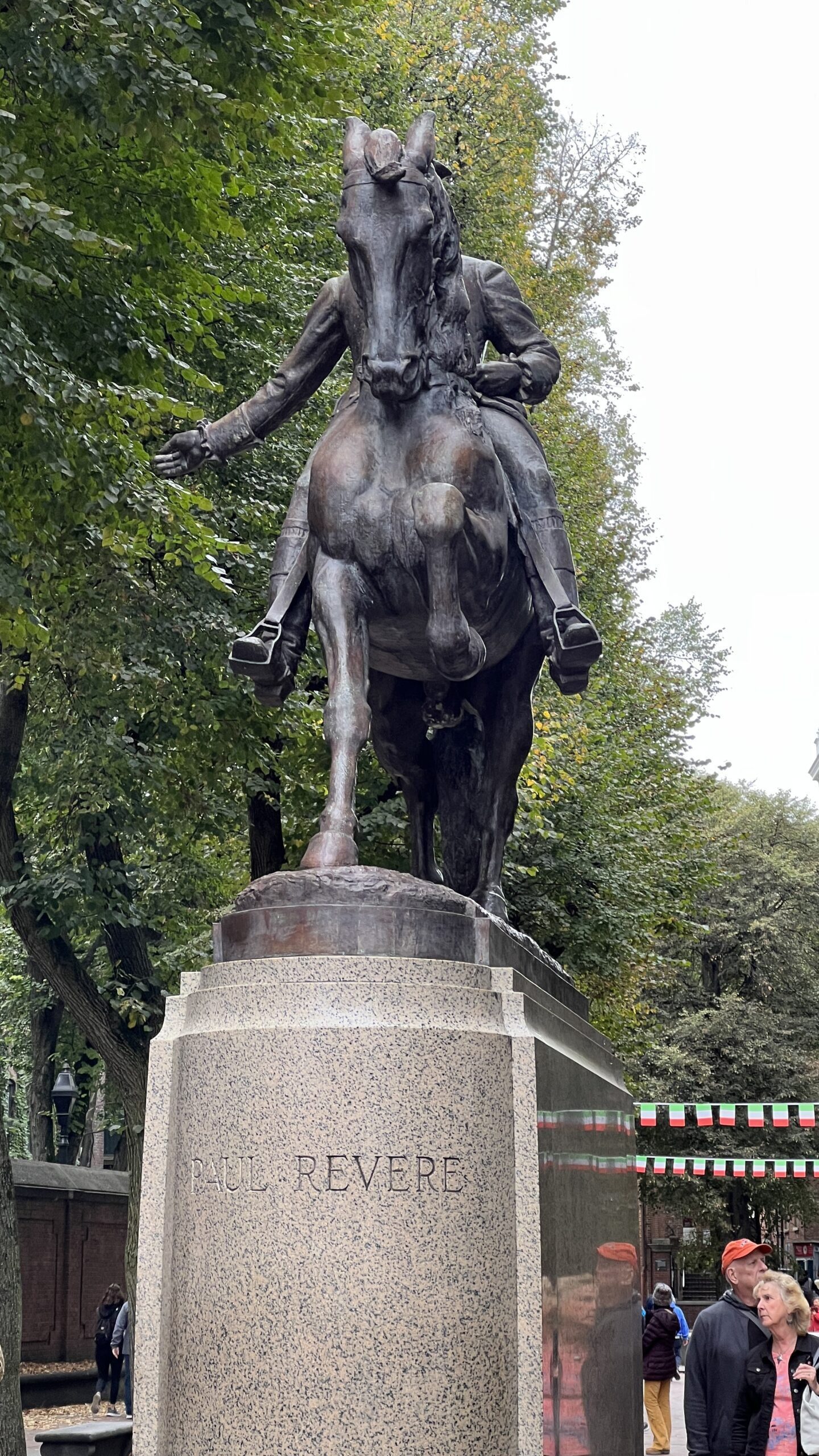 Close-up of bronze equestrian statue showing Paul Revere on horseback from below, with name engraved on granite pedestal base